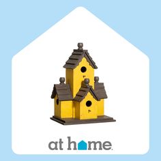 a yellow birdhouse sitting on top of a blue and white sign that says at home