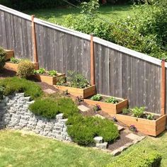 a wooden fence with several planters in the middle and flowers growing out of them