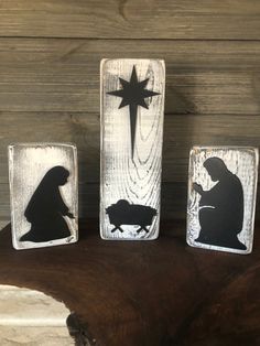 three wooden magnets depicting nativity and the birth of jesus on a tree stump