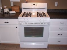 a white stove top oven sitting inside of a kitchen next to cabinets and counter tops