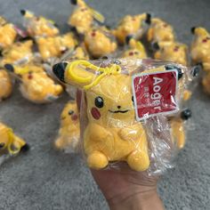 a person holding up a small yellow stuffed animal in front of many other toy figurines