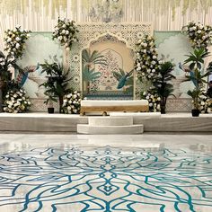 an elaborately decorated room with blue and white flowers on the floor, surrounded by greenery