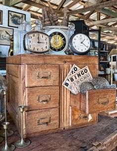 an old wooden cabinet with many clocks on top of it and other items around the room