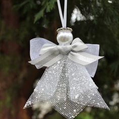 a white ornament hanging from a tree with a bow and pearls on it