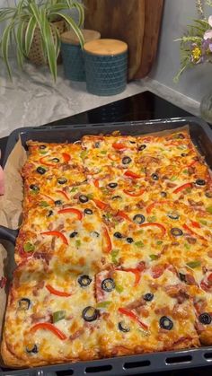 a person holding a spatula in front of a large pizza on a baking sheet