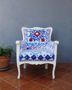 a blue and white chair sitting on top of a tile floor next to a potted plant