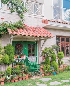 a green chair sitting in front of a building with potted plants on the outside