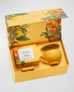 a yellow tea set in a gift box with flowers on the lid and matching accessories