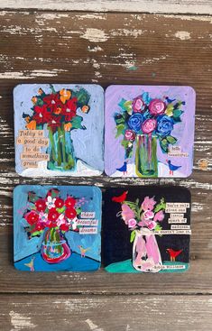 three coasters with flowers painted on them sitting on a wooden surface, one has a card and the other has an envelope