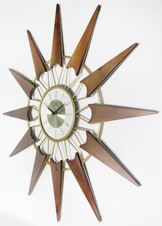 The Nova wall clock gets its inspiration from the clean, natural wood tones and gold metallic from the turn of the century. Oversized at almost 31 inches in diameter, this is a great pick for hanging in your den, living room, or bedroom. At the center of the starburst, there is a circular metallic gold frame displaying numbers against a silver face. The clock face is majestically surrounded by aged solid wooden rays. Pair it with geometric accent pieces and you will have a space that gives the i Sunburst Clock, Mid Century Wall Clock, Wood Composite, Turn Of The Century, Clock Face, Composite Wood, Brown Gold, Gold Frame, Accent Pieces