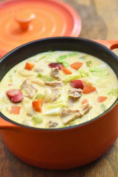 a bowl of soup with carrots, celery and meat in it on a wooden table