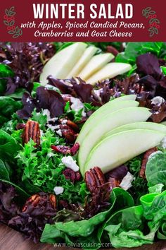 a salad with apples, lettuce and pecans in it on a wooden platter