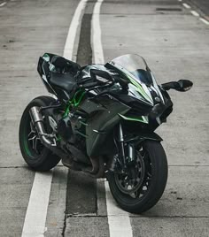 a black and green motorcycle parked on the side of the road next to a street