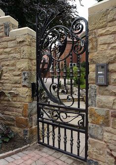 an iron gate is open on a brick walkway