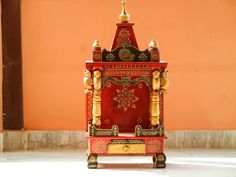 a small red and gold shrine in front of an orange wall