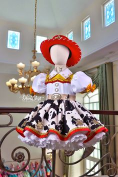 the doll is wearing a red hat and black and white dress with cow print on it