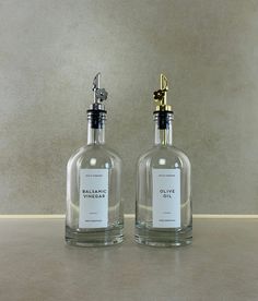 two clear glass bottles with gold handles and labels on them