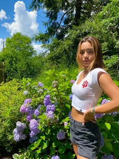 a woman standing in front of purple flowers with the caption hype & vice