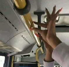 a woman's hands reaching up to grab something off the ceiling on a bus