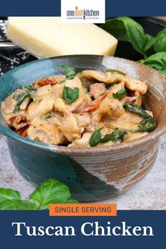 a bowl filled with pasta and spinach on top of a table next to cheese