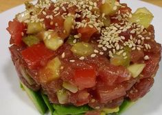 a white plate topped with meat and veggies covered in sesame seed toppings