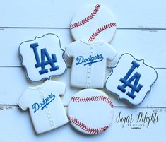 cookies decorated to look like baseballs and jerseys with the number four on them, sitting on a white wooden surface