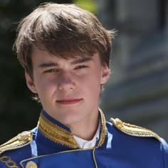 a young man wearing a blue uniform with gold trimmings on his chest and shoulder