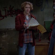 two young men standing next to each other in front of graffiti covered walls and writing on paper