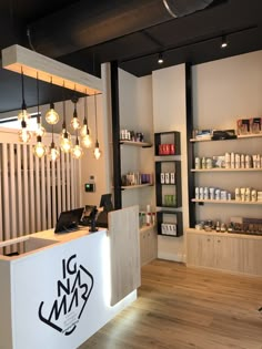 the inside of a hair salon with lights hanging from the ceiling and shelving on the wall