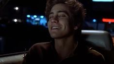 a young man sitting in the back seat of a car at night with his eyes closed