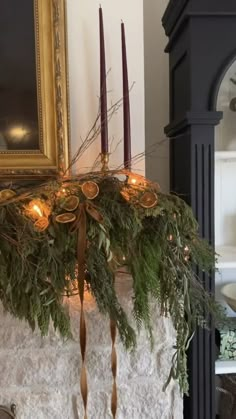 a mantle with candles and greenery on it