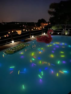 the pool is lit up with colorful lights and floating decorations on it's sides