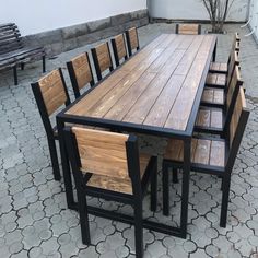 an outdoor table and chairs made out of wood with black metal legs on a patio