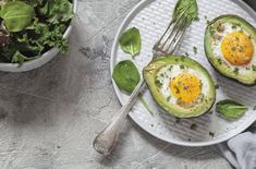 an avocado with eggs and spinach is on a plate next to a fork