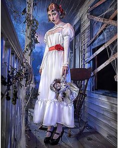 a woman in a white dress is standing on a porch