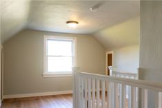 an empty room with hard wood floors and white railing