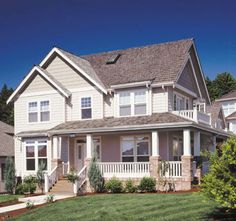 two story house with front porch and wrap around deck on grass lawn in residential area