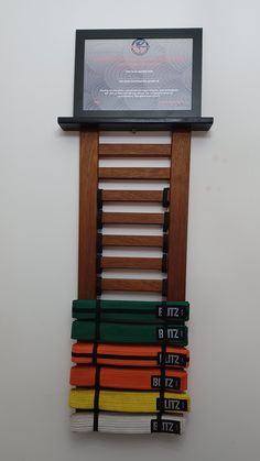 a wall mounted display with many different colored belts hanging on it's back side