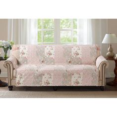 a living room with a couch covered in pink and white floral print fabric, next to a window