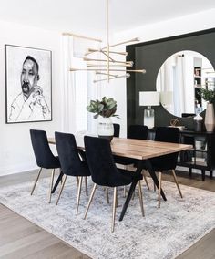 a dining room table with black chairs and a rug on the floor in front of it