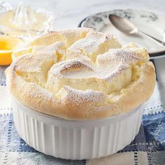 a pie with powdered sugar on top sits in a dish next to an orange