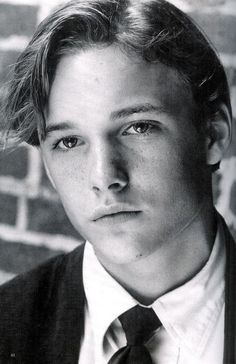 a black and white photo of a young man wearing a suit with a tie on