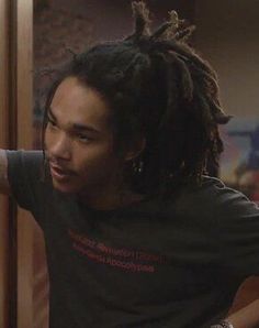 a man with dreadlocks standing in front of a door