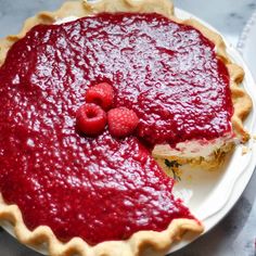 a pie with raspberries on top and one slice missing from it, sitting on a plate