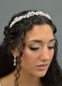 a woman wearing a tiara with flowers on her head and hair comb in her hand