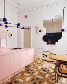 a kitchen with pink cabinets and blue balls hanging from the ceiling, along with an oval dining table