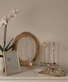 there is a mirror, vase with flowers and jewelry on the table