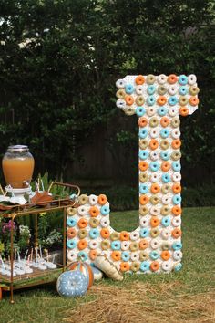 a large letter made out of doughnuts sitting on top of a grass covered field