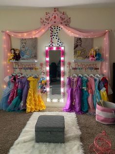 a room filled with lots of princess dresses and lights on the walls, including a large mirror