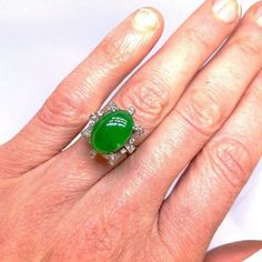 "A custom made one of a kind 1950s natural untreated earth mined A-Type jadeite and fine white diamond hand made ring in 18K white gold.  This exceptional mid-century ring is a custom hand made piece which is one of a kind. The central A-type jadeite cabochon is translucent and has exceptional vivid green color. It sits in a beautiful setting which is reminiscent of butterflies and bows that is set with the finest quality VS D diamonds.  The beautiful jadeite jade in this handmade vintage ring i Green Cabochon Rings In Art Deco Style, Green Cabochon Art Deco Rings, Art Deco Green Cabochon Rings, Unique Oval Jade Rings, Collectible Jade Gemstone Rings, Jade Diamond Ring, Jade Engagement Ring, Diamond Butterfly Ring, Modern Rings